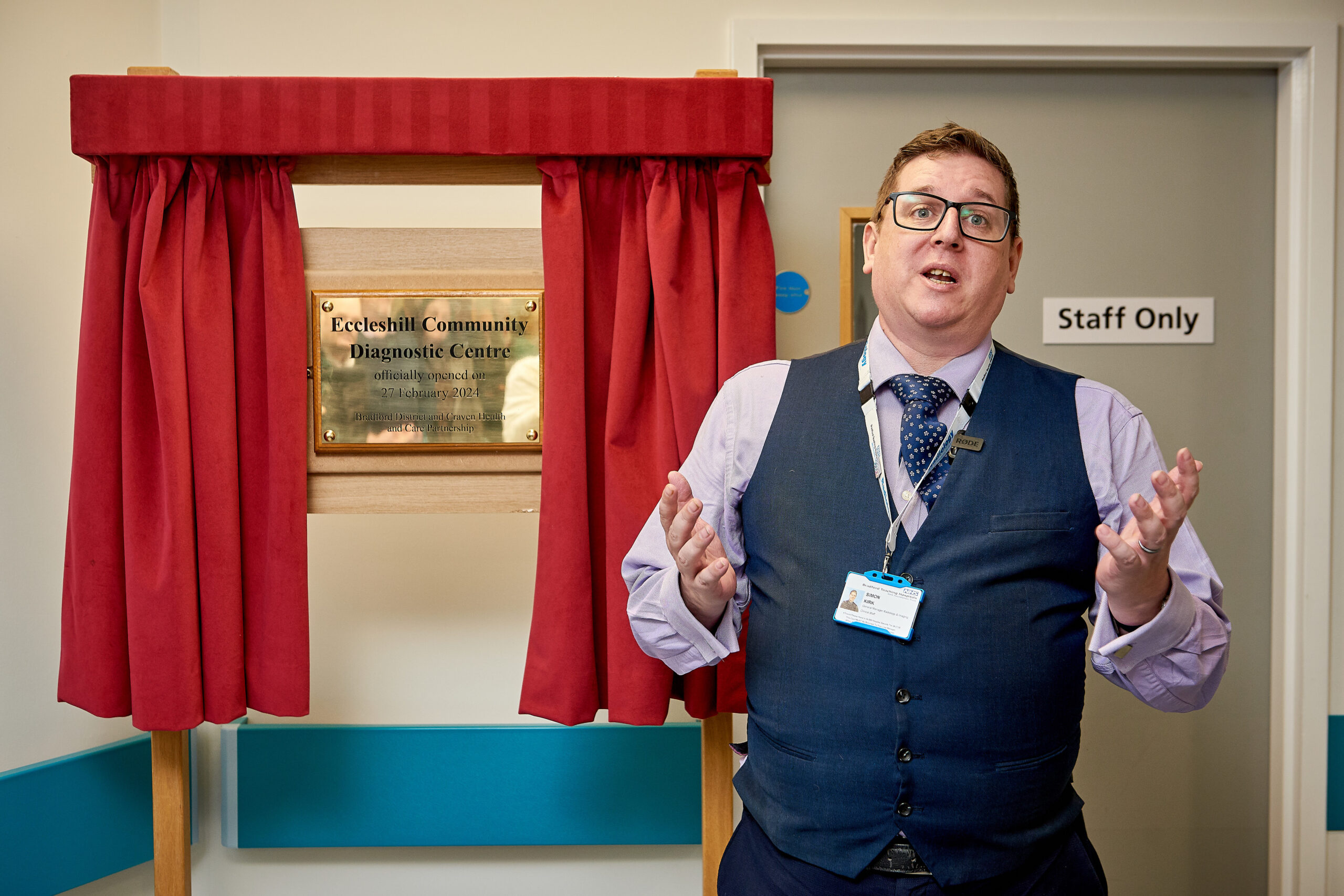 Picture of Simon Kirk in front of Eccleshill Community Diagnostic Centre plaque.