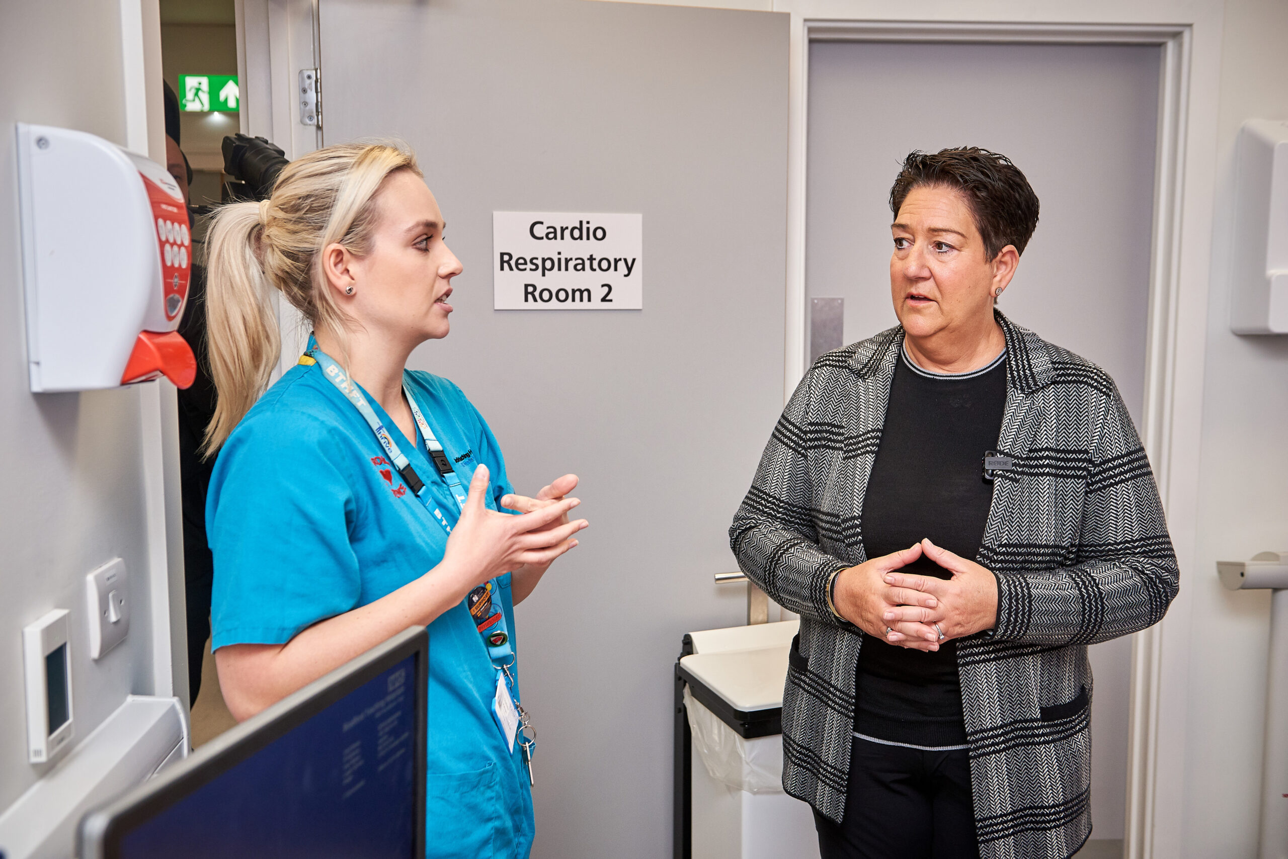 Mel pickup talking to radiologist in blue scrubs.