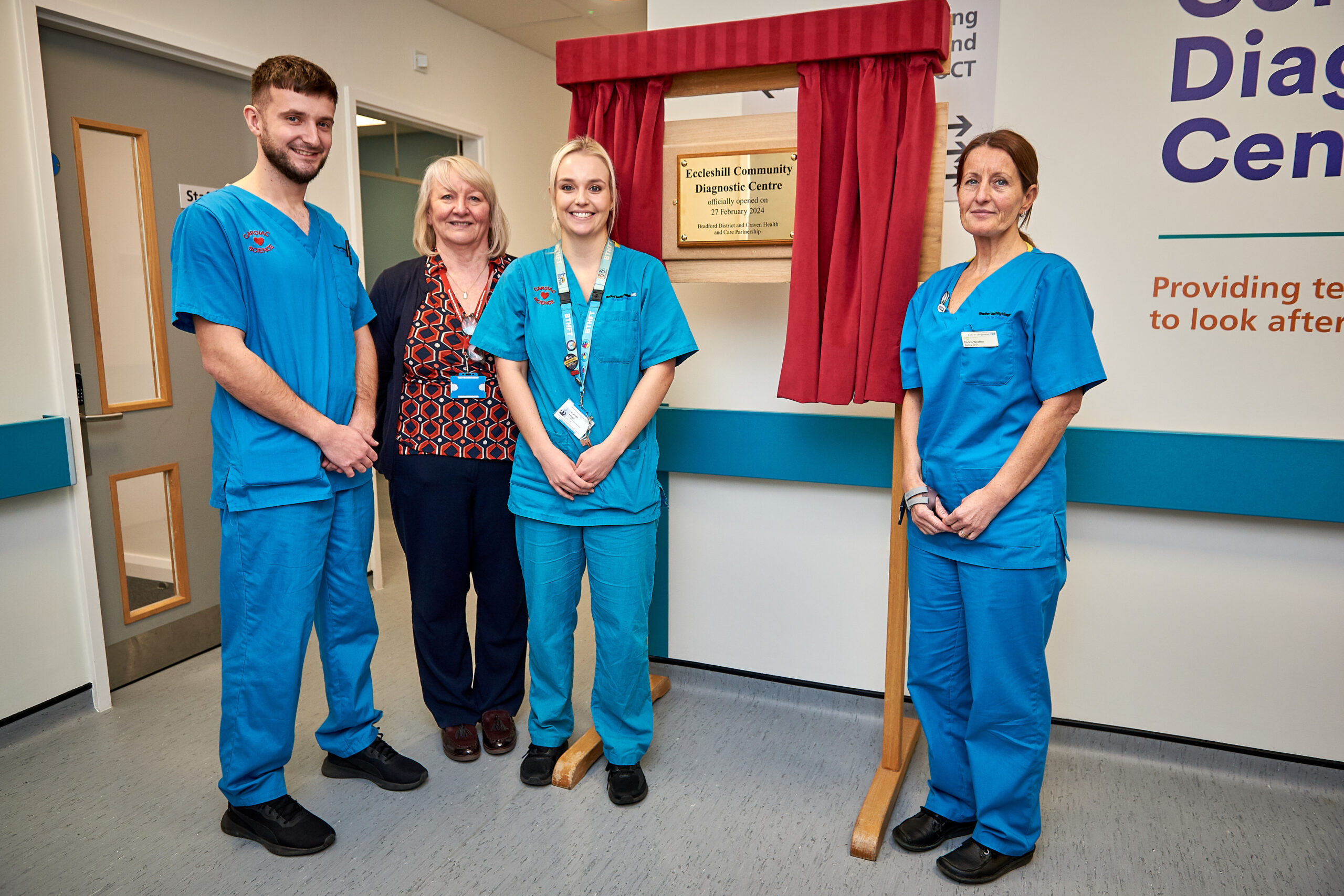 Picture of four people in front of a plaque.
