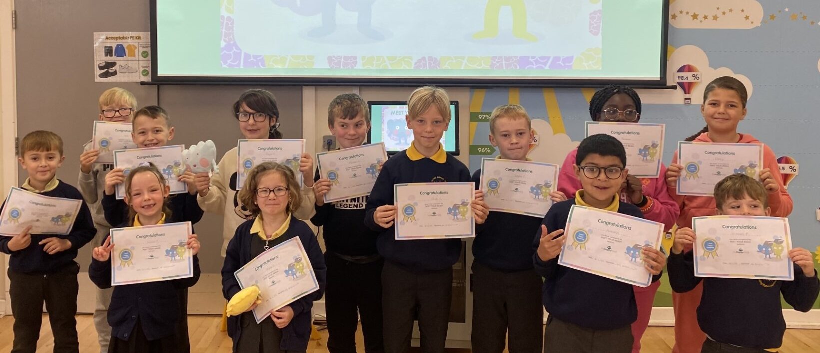 Children at an assembly holding certificates.
