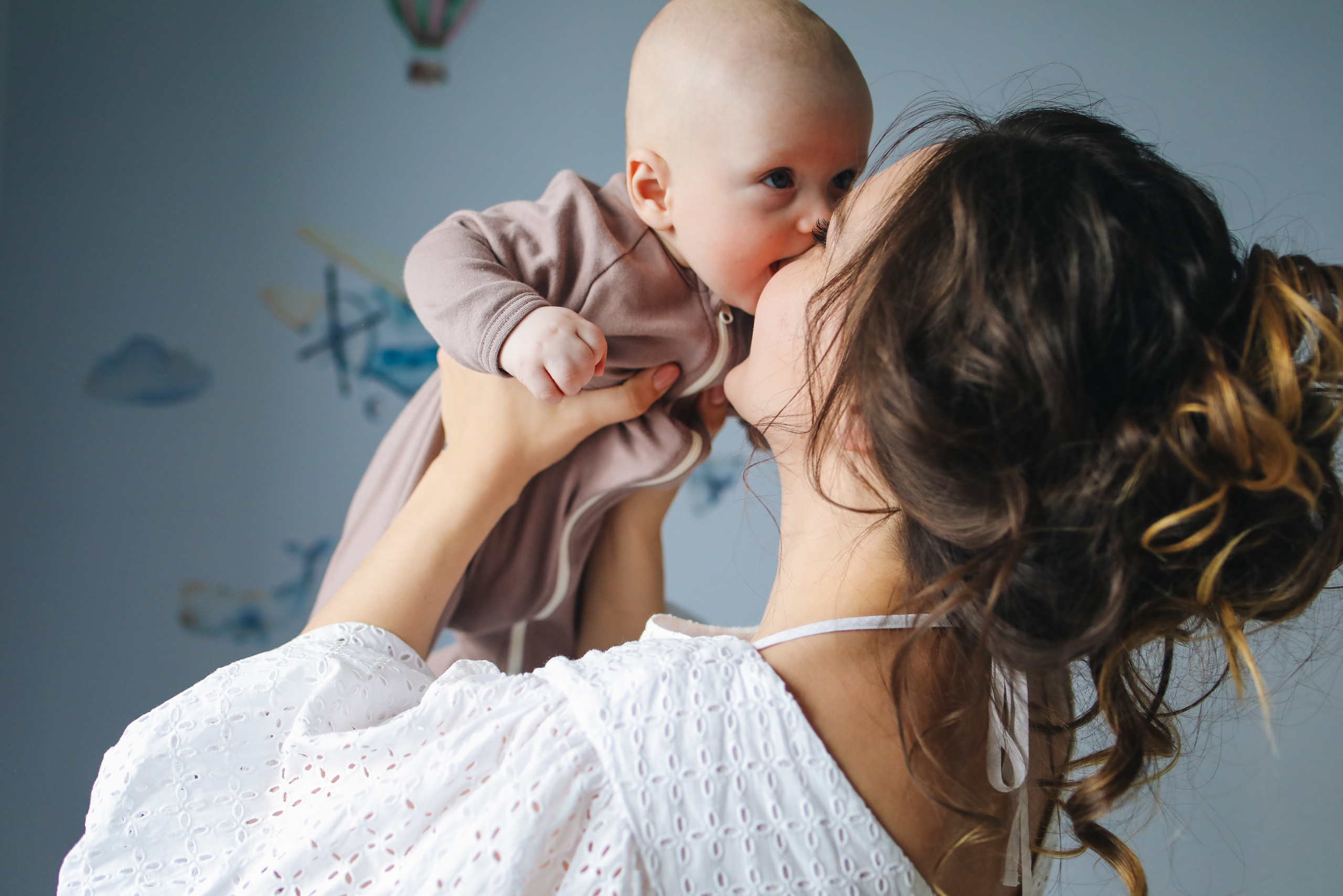 Woman holding a baby up in the air and kissing it