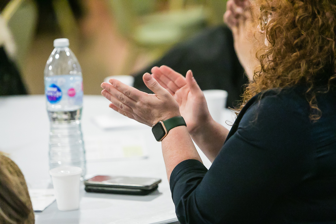 A hand clapping with a water bottle next to it