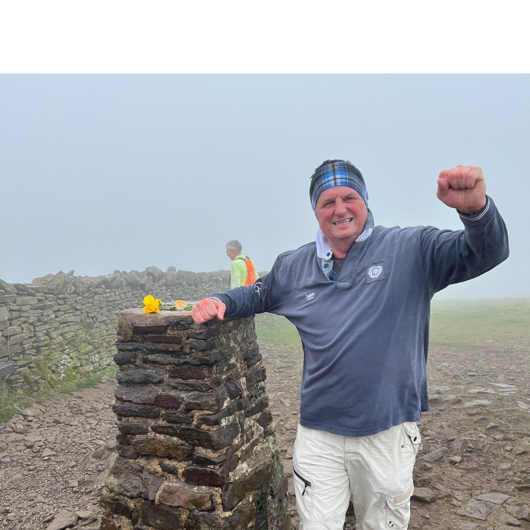 A man raising his arm while standing against a rock