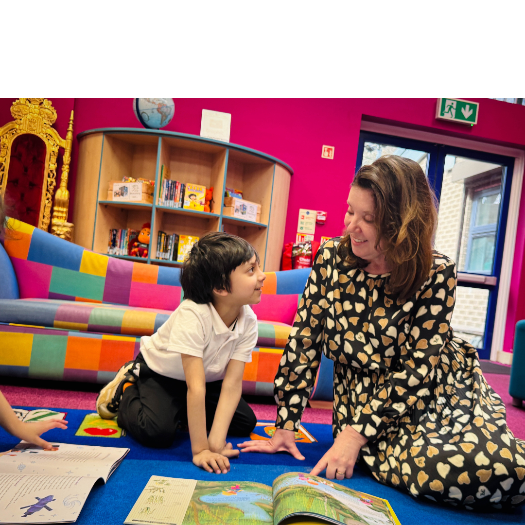 A woman sat on a mat reading a book with a young child