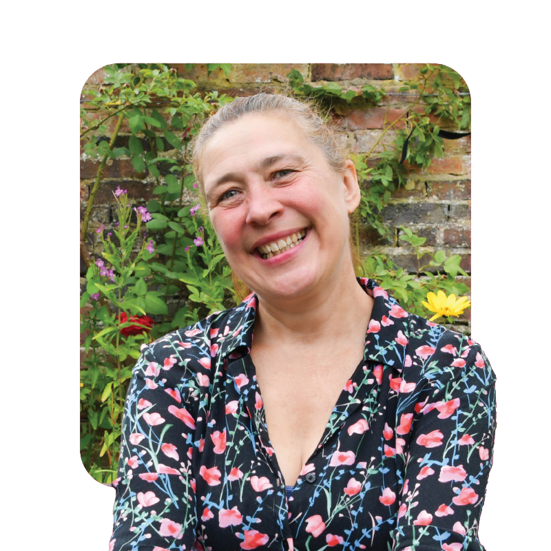 Smiling woman in a floral shirt sitting in a garden, sharing her experience with cancer screening.