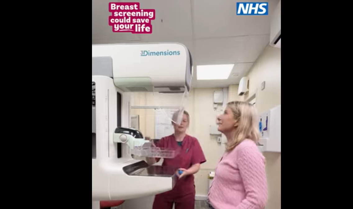 Two women looking at a mammogram machine
